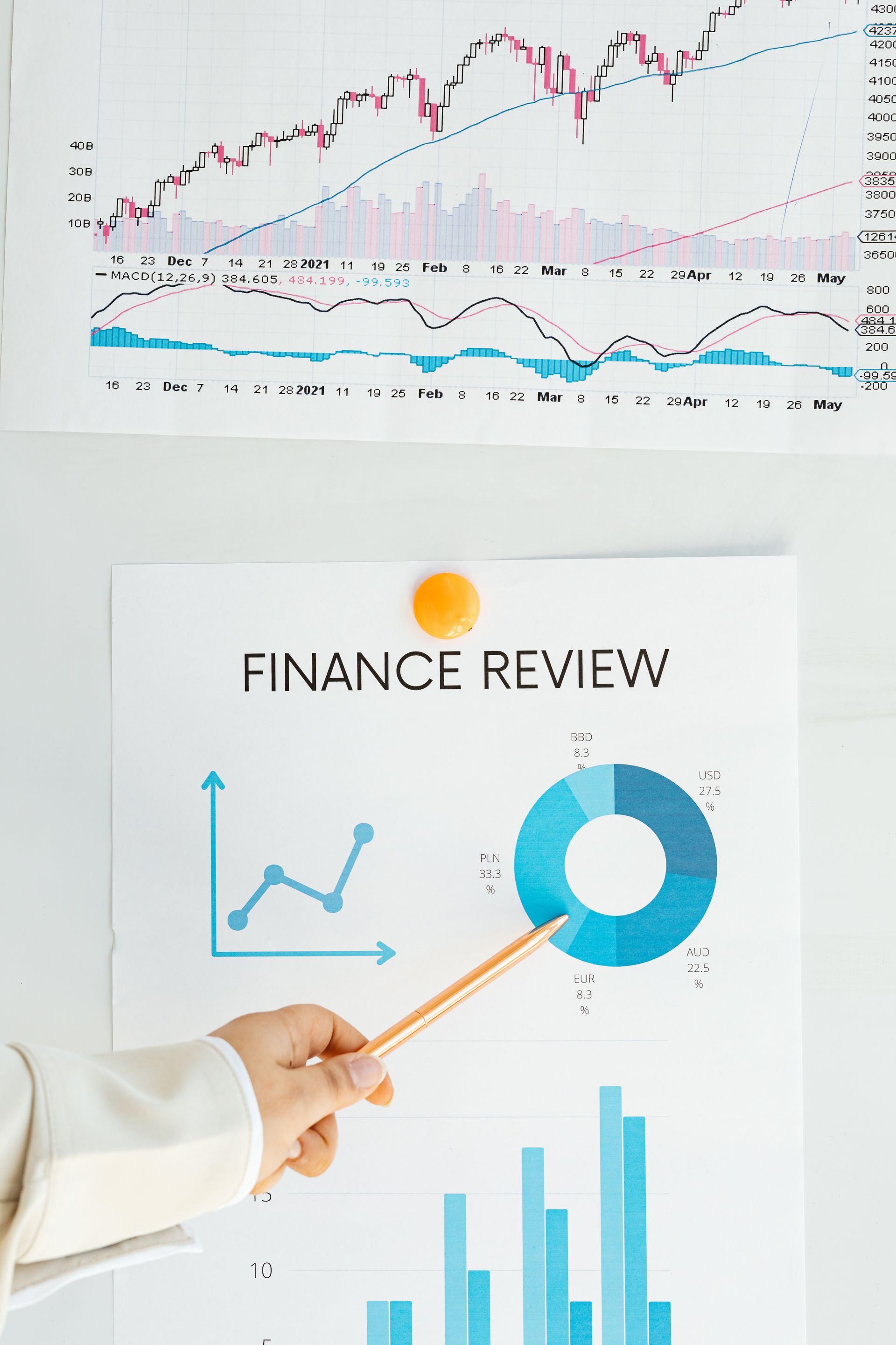 Hand pointing at a printed finance report with a blue donut chart and bar graph