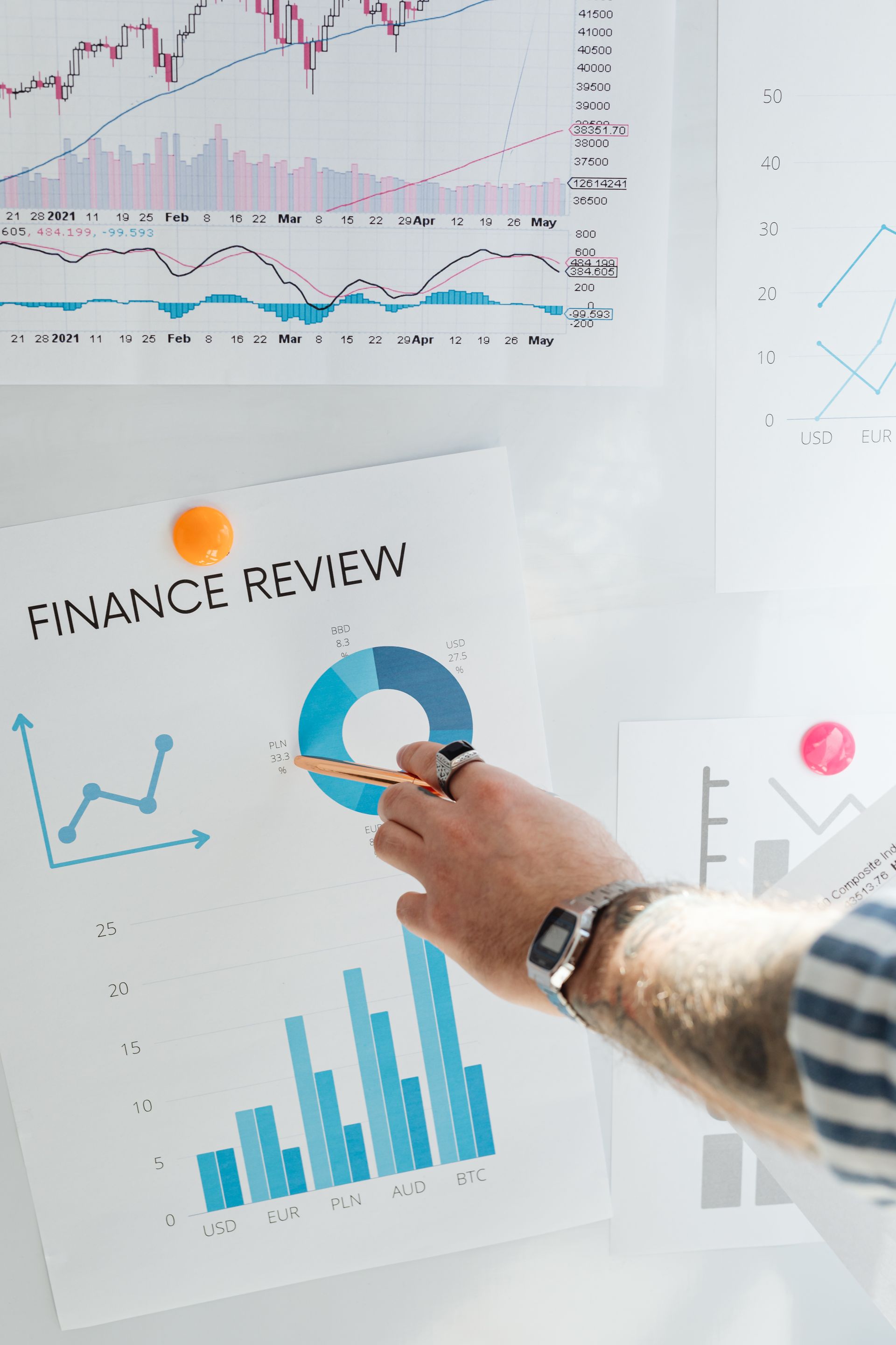 Hand pointing a pen at a printed finance report with bar chart and blue donut